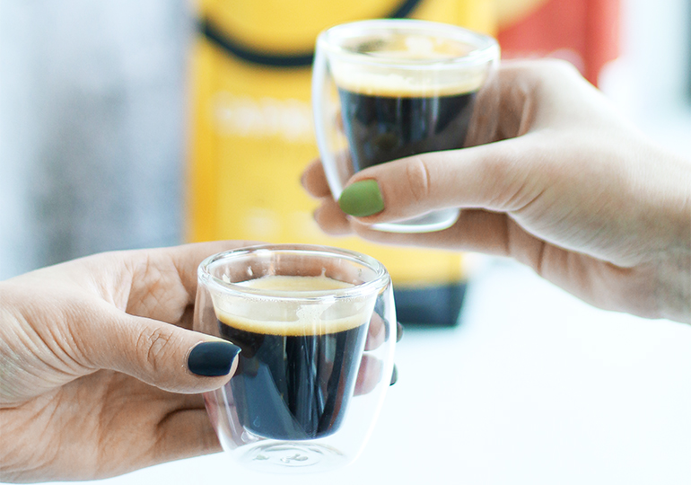 Dwie szklanki kawy espresso trzymane w dłoniach