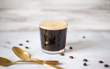 Szklanka kawy espresso lungo między ziarnami kawy